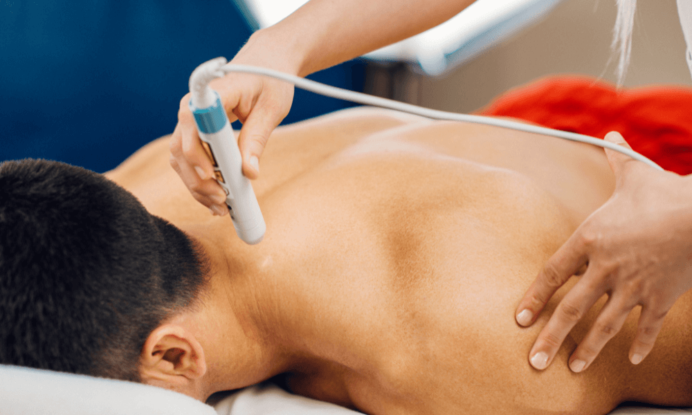 A practitioner uses a handheld ultrasound device on a patient's neck during a treatment session.